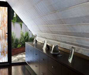 motorized skylight shades over a dark brown dresser in a Hamptons home
